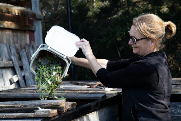 Marika Nabung empties her compost bin into the large compost at a community garden in Rose Bay.