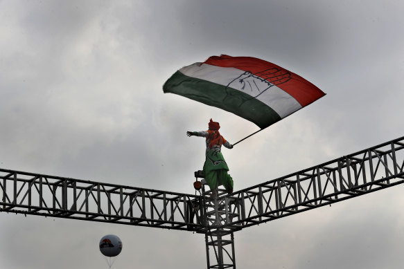 An opposition Congress party worker waves a party flag atop steel scaffolding at a rally protesting against the "anti-people" policies of Prime Minister Narendra Modi  in New Delhi.