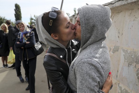 A Russian recruit and his wife kiss outside a military recruitment centre. 