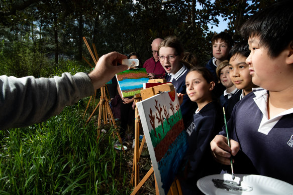 Year 6 student Darsi Vukelja (centre) paints Johnstons Creek with her classmates. 