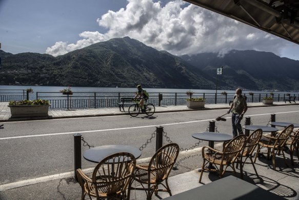 A cyclist rides past cafe tables in Tremezzo, Lake Como, Italy.