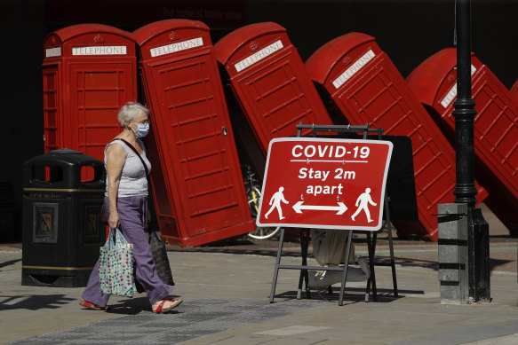 A social distancing sign is displayed in front of "Out of Order" a 1989 red phone box sculpture by British artist David Mach, in London.
