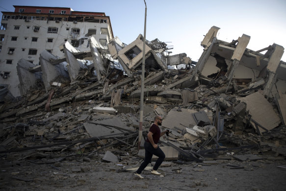 A Palestinian man passes by the remains of a building destroyed by Israeli airstrikes on Gaza City.