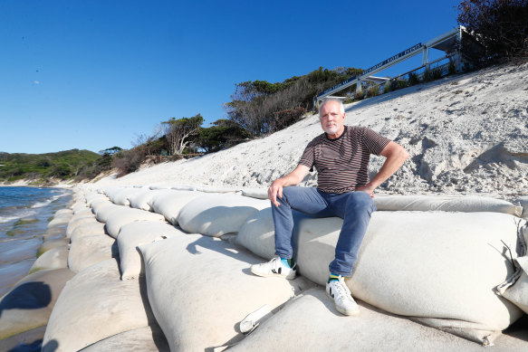 Beach Byron Bay restaurant owner Ben Kirkwood sits on a sandbag placed to save his business at Clarkes Beach. 