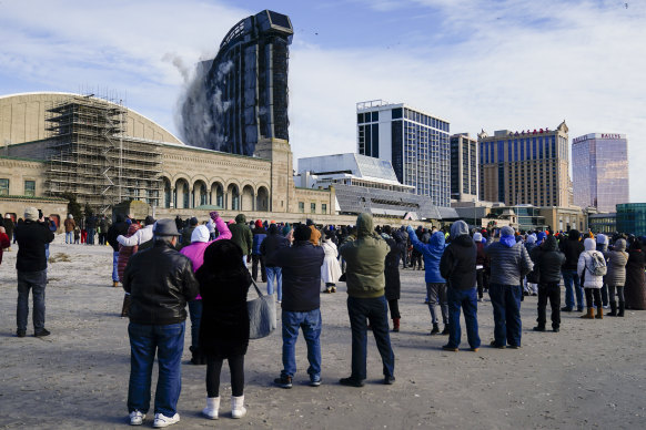 People gather to watch as the former Trump Plaza casino is demolished in a controlled explosion.