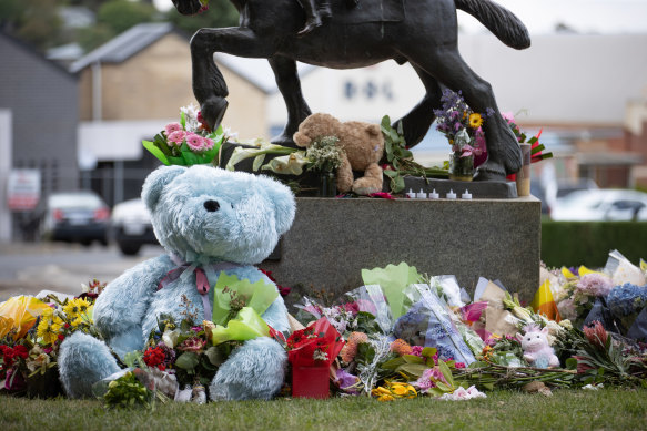 Flowers and toys at the base of a statue near the crash scene. 