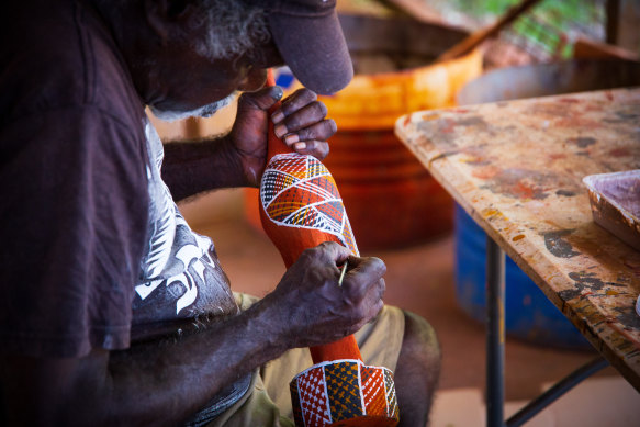 A Tiwi Island artist painting a carved wooden bird. 