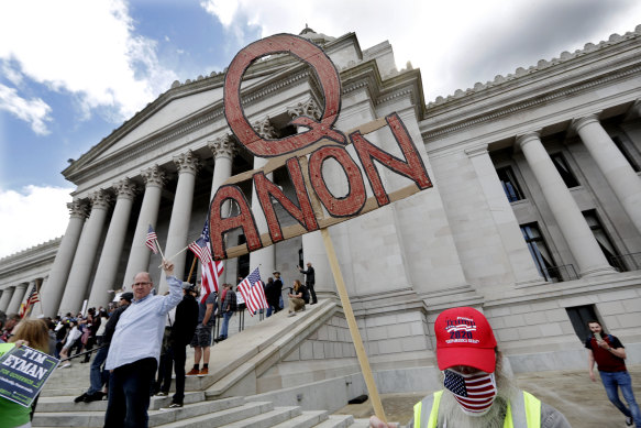 A demonstrator holds a QAnon sign as he walks at a protest opposing Washington state's stay-home order. 