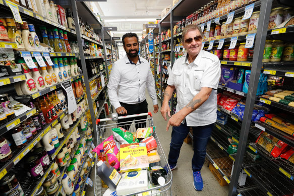 Altona IGA owner Hitesh Palta, left, with a customer. His supermarket was the first to introduce an elderly-only shopping hour.