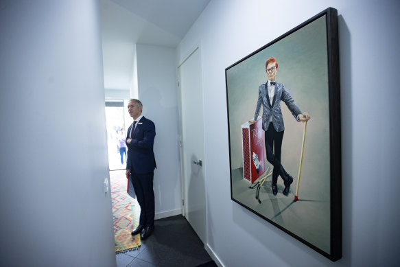 Auctioneer Jarrod Couch stands by a portrait of Rhys Nicholson before the auction. 