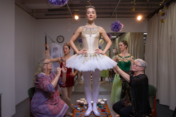 Volunteers Naomi Otton and Marcia Bergh put the finished touches on dancer Benedicte Bemet’s dress.