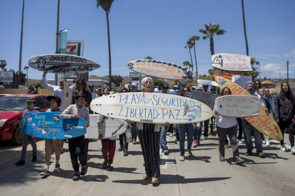 Locals in Ensenada, Mexico, march  to protest the disappearance of foreign surfers. Surfboard signe, centre, reads: “Beaches - safety - freedom - peace”.