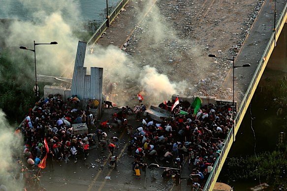 Anti-government protesters take cover while Iraq security forces fire tear gas during a demonstration in Baghdad, Iraq on Saturday.