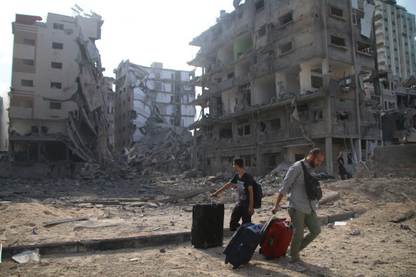 Palestinian citizens evacuate their homes damaged by Israeli airstrikes.