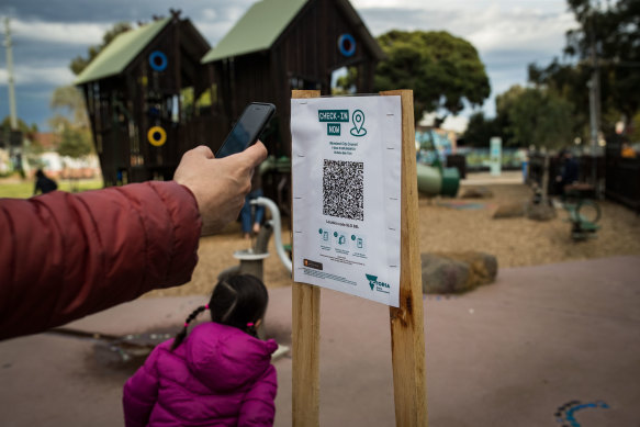 A parent uses a QR code check at a playground in Brunswick when they were reopened in early September.