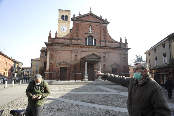 People wear masks as they stand in front of the San Biagio church in Codogno, near Lodi, northern Italy.