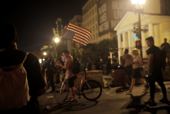 A protester holds an upside-down American flag inscribed with "Black lives matter," during protests on Independence Day at a street in Washington that's been renamed Black Lives Matter Plaza.