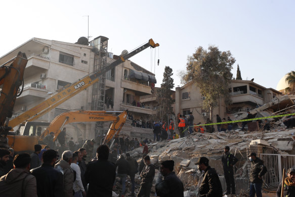 Emergency services work at a building hit by an air strike in Damascus blamed on Israel.