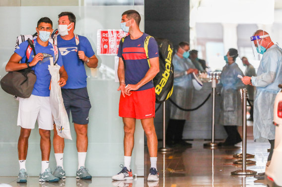 Players wait in front of the Grand Hyatt Melbourne, with staff in full PPE.