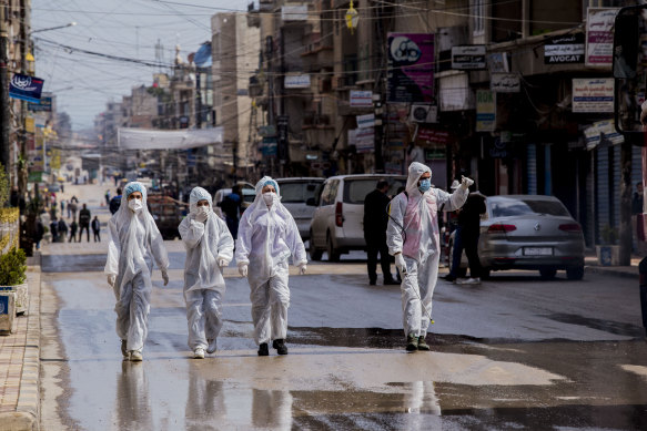 Medical workers oversee the disinfection of streets aiming to halt the spread of the new coronavirus in Qamishli, Syria.