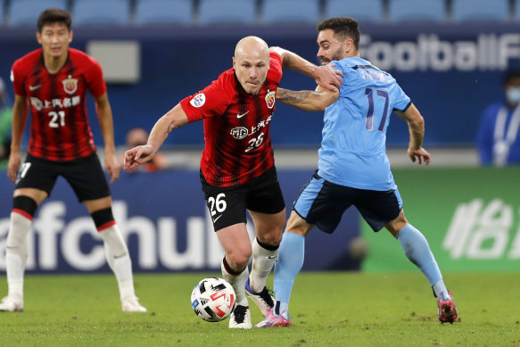 Aaron Mooy pushes past Sydney FC midfielder Anthony Caceres.