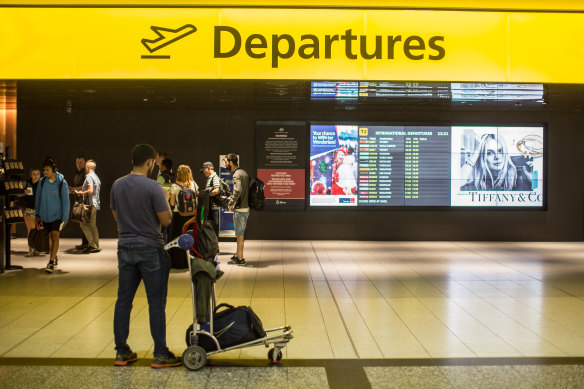 Passengers queue past the departures sign at Melbourne Airport. 
