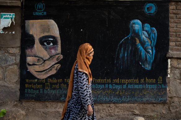 A woman walks past a mural calling for women and children’s rights in Bamian, Afghanistan.