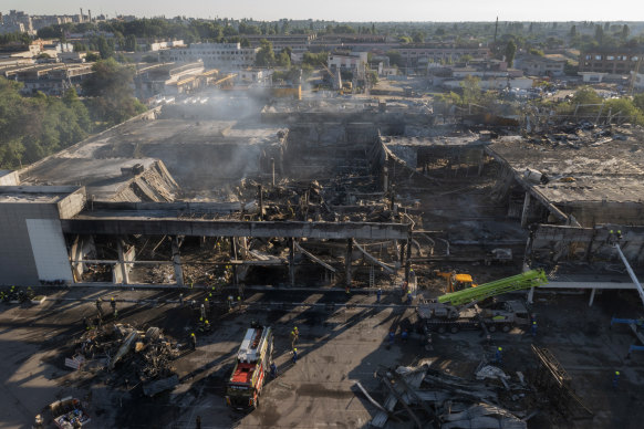 Ukrainian firefighters work to clear debris at a shopping centre destroyed by a rocket attack in Kremenchuk.