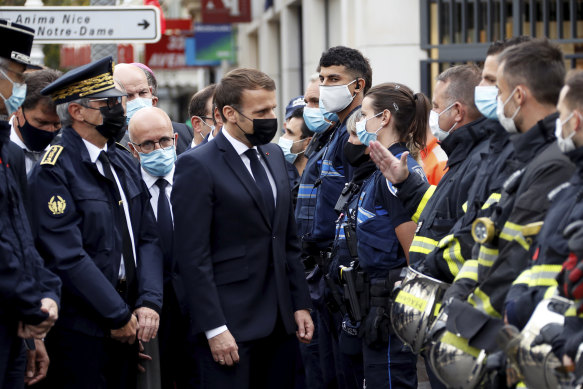 French President Emmanuel Macron meets police and rescue workers outside the cathedral in Nice.