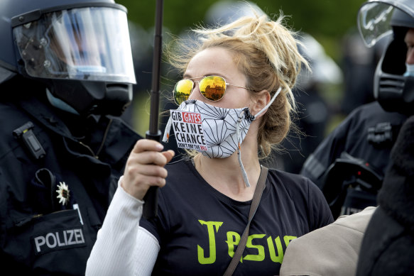 The Reichstag building, home of the German federal parliament, is mirrored in the glasses of a woman wearing a face mask with the slogan"Don't Give (Bill) Gates A Chance"