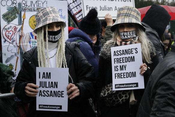 Two supporters wear masks and hold signs during a protest against the extradition of Wikileaks founder Julian Assange outside Belmarsh Magistrates Court in London, 