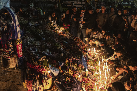 People and supporters of Arema FC light candles as they pay condolence to the victims outside Kanjuruhan Stadium in Malang, Indonesia.