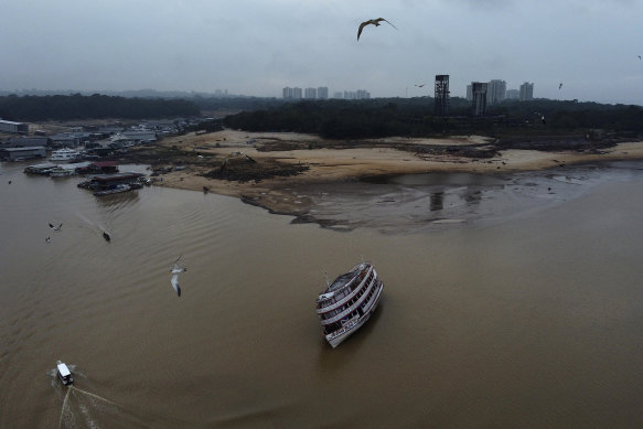 A boat is stuck in the Negro River during a drought in Manaus, Amazonas state, Brazil, on Monday. The high rises of the Manaus CBD are visible in the background.