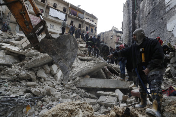 Syrian Civil Defence workers and security forces search through the wreckage of fallen buildings, in Aleppo.