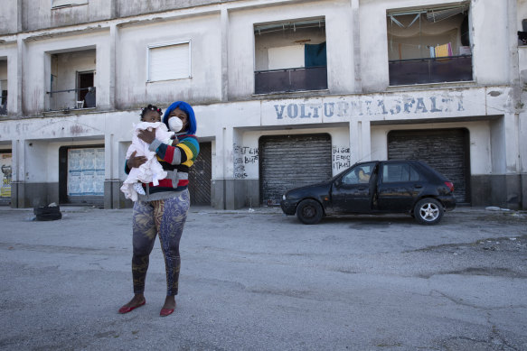 An undocumented worker holds her baby as she walks around the migrant neighbourhood in Castel Volturno, near Naples 