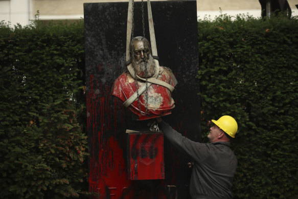 A bust of King Leopold II is hoisted off of its plinth by a crane in a park in Ghent, Belgium, on Tuesday.