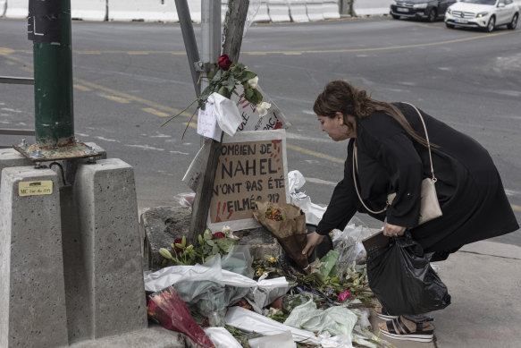 Nahel M.'nin cenazesinden kısa bir süre sonra, 1 Temmuz'da Fransa'nın Nanterre kentinde öldüğü yerde bir kadın saygılarını sunuyor.