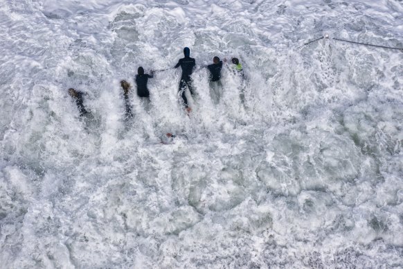 Children hold the fence chains at North Narrabeen rockpool as huge waves hammer the Sydney coast and other parts of NSW.