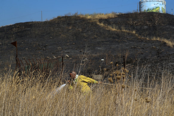 An Israeli firefighter attempts to extinguish a fire caused by rocket near the northern Israeli town of Kiryat Shmona.