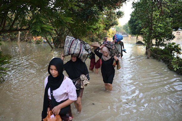 People carry their belongings as they wade through the water at a flooded village in Bireun, Aceh province, Indonesia on Saturday.