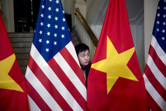 A worker arranges American and Vietnamese flags before a diplomatic event in Hanoi in 2019.