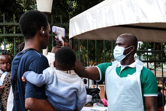 Un funzionario sanitario utilizza un termometro per controllare le persone davanti all'ospedale musulmano Kibuli di Kampala, in Uganda.