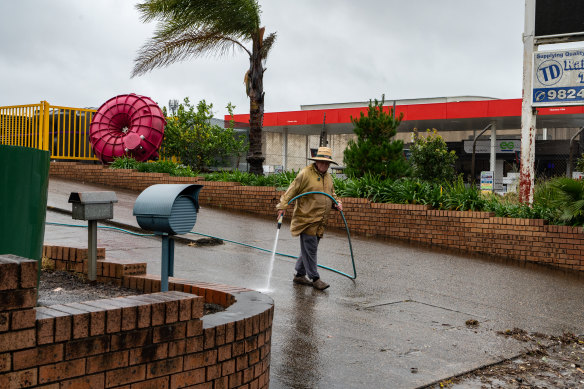 A man cleaning a driveway in an area affected by floods in Moorebank, in western Sydney, on Monday.