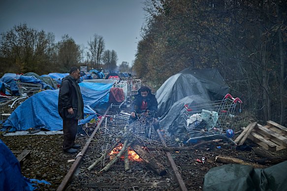 Asylum seekers light a fire to keep warm at daybreak next to an old railway line in Dunkirk, France. 