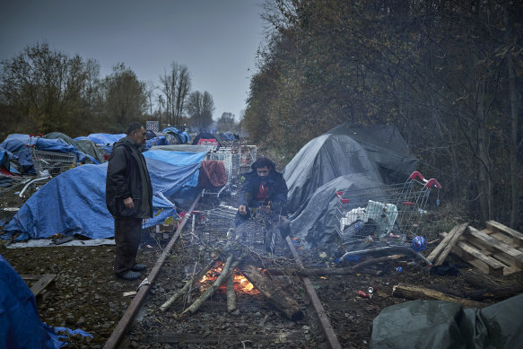Asylum seekers light a fire to keep warm at daybreak next to an old railway line in Dunkirk, France. 
