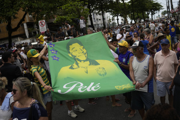 People hold a banner of the late Brazilian soccer great Pele.