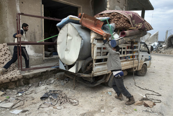 An armed resident loads his truck with belongings during a visit to his home in Balyoun, Syria.