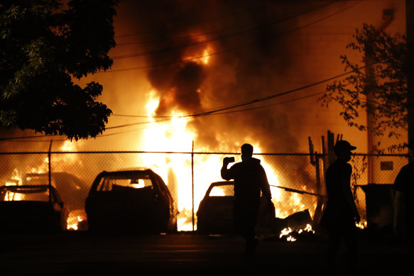 People watch a fire in Minneapolis on Friday. Protests continued following the death of George Floyd who died after being restrained by Minneapolis police officers on Monday.