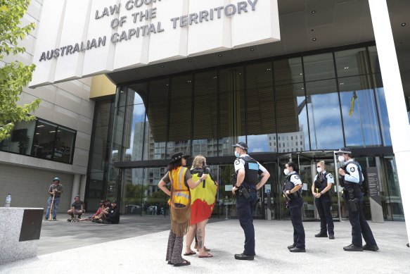 Police speak with protesters outside the ACT Magistrates Court during a hearing for the man who has been charged with alleged arson at Old Parliament House.