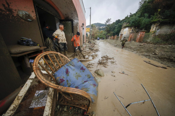 People stand in front of a flooded shop after heavy rainfall triggered landslides in Ischia.